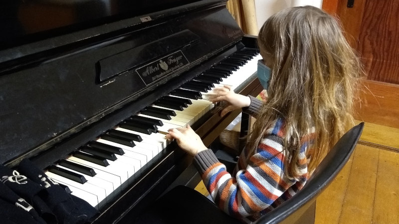 Kind mit Maske in Corona-Quarantäne: Wenigstens Klavierspielen ist noch erlaubt